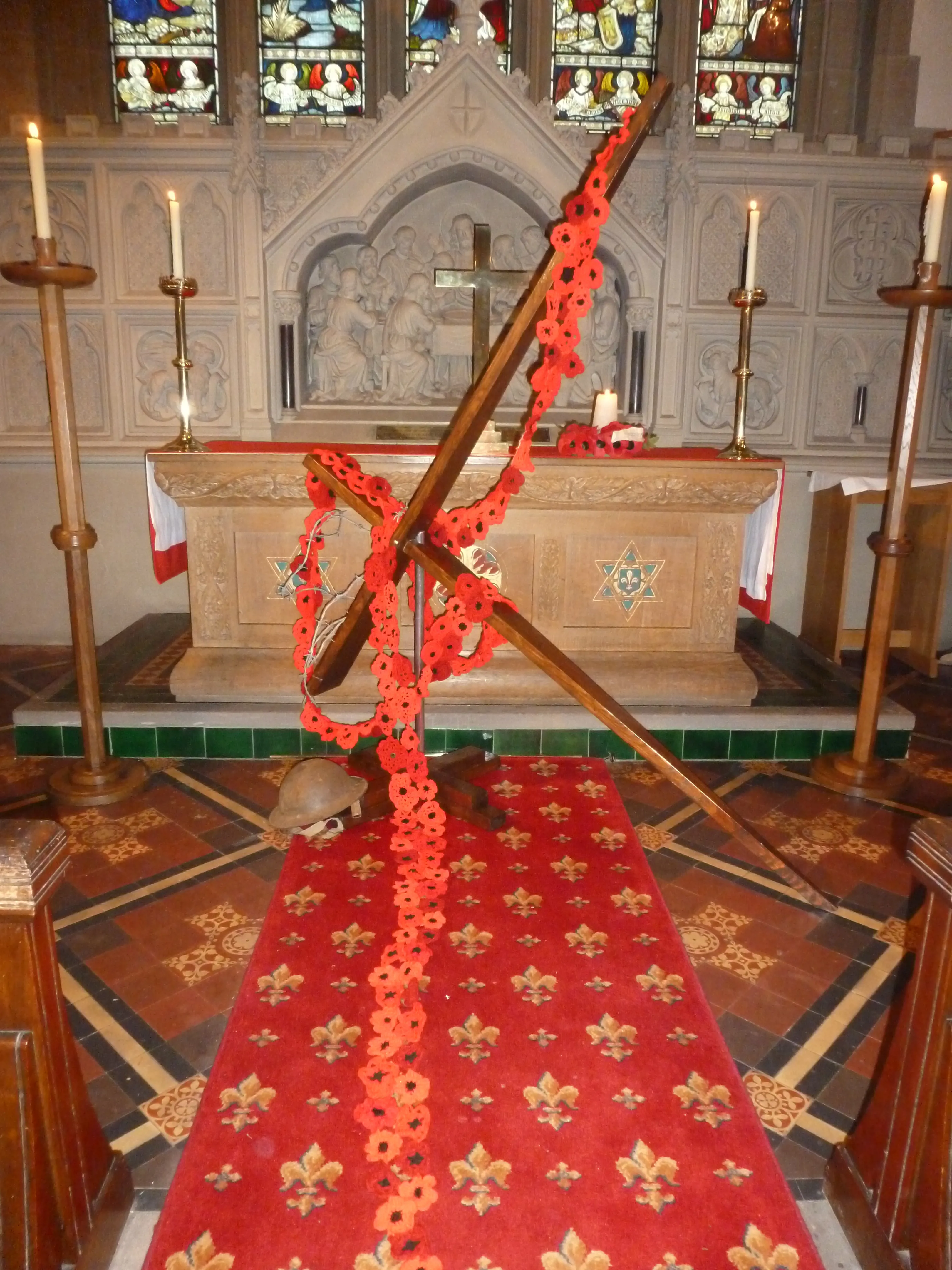Cross draped with poppies leaning against the altar
