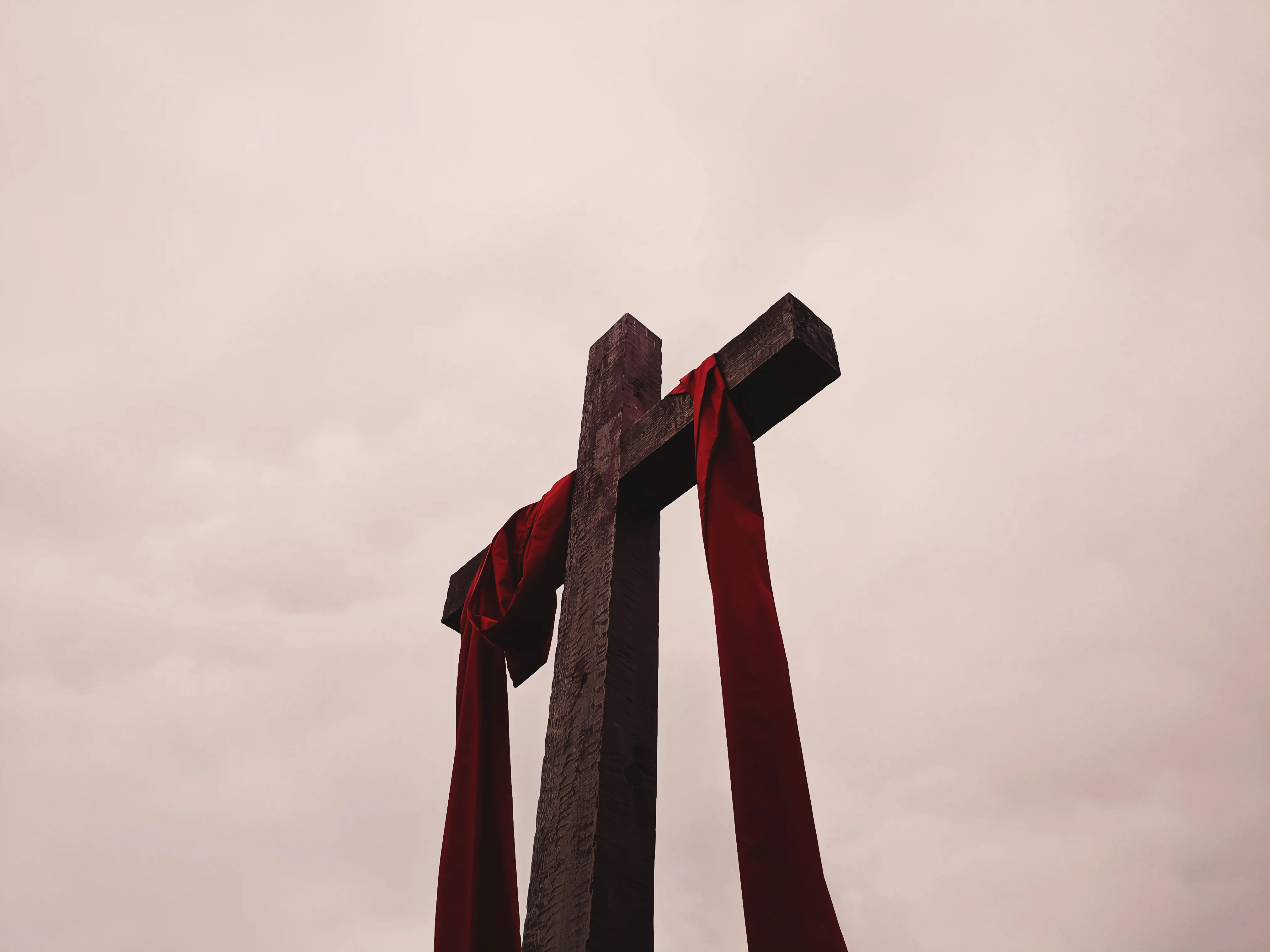 A wooden cross with a red cloth draped over it.