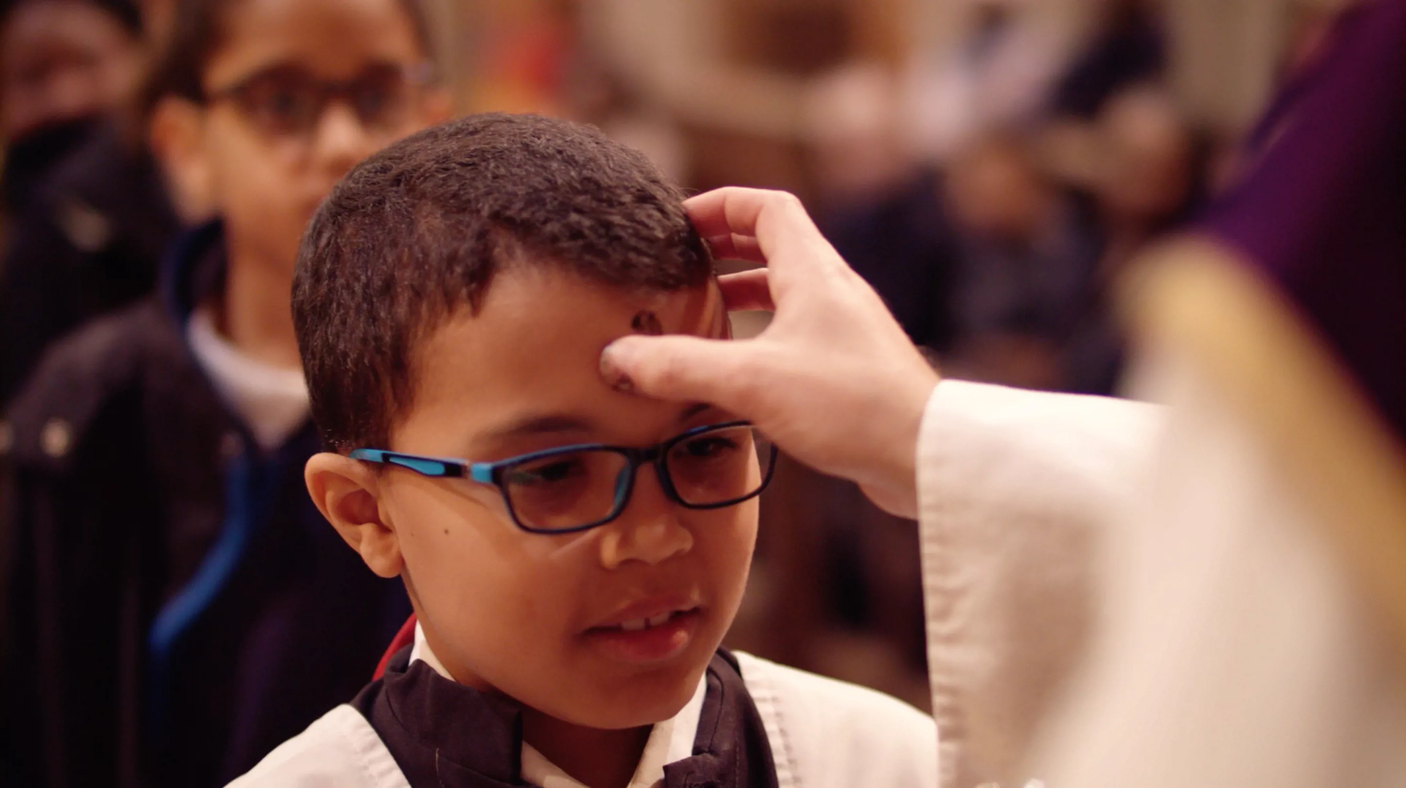 Boy having an ash cross made on his forehead.