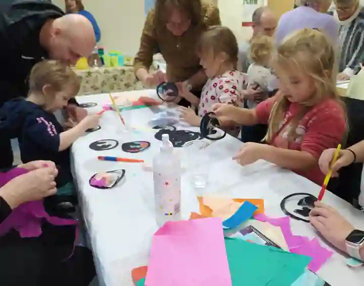 Children doing craft activity with adults helping them.