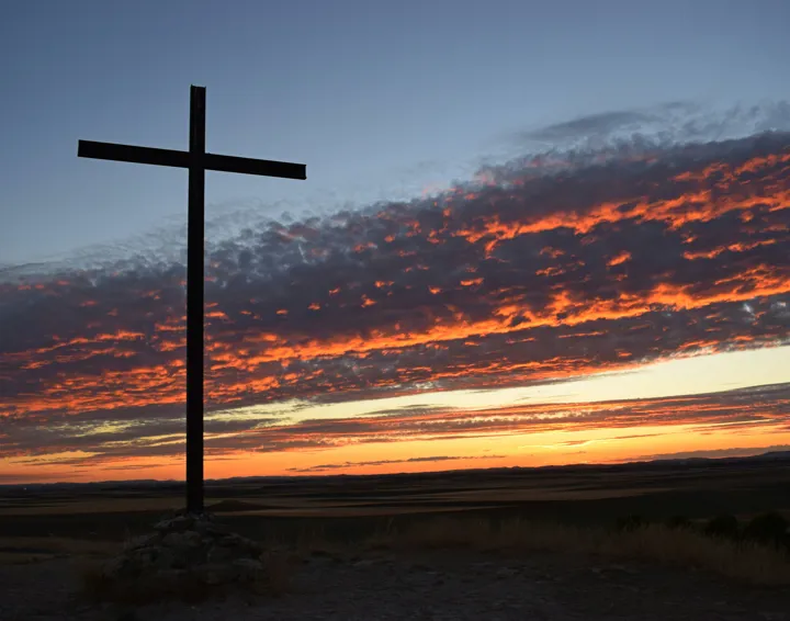 A cross with a sunset sky behind