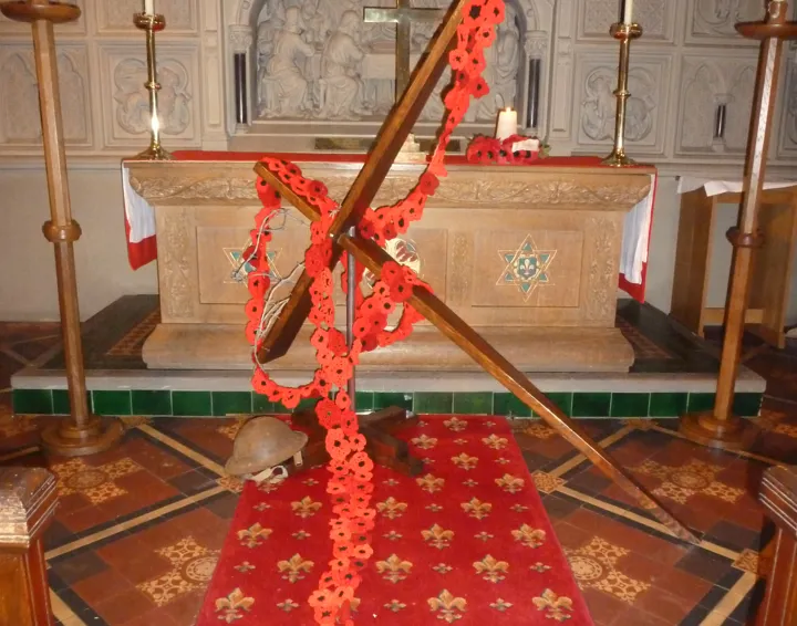 Cross draped with poppies leaning against the altar