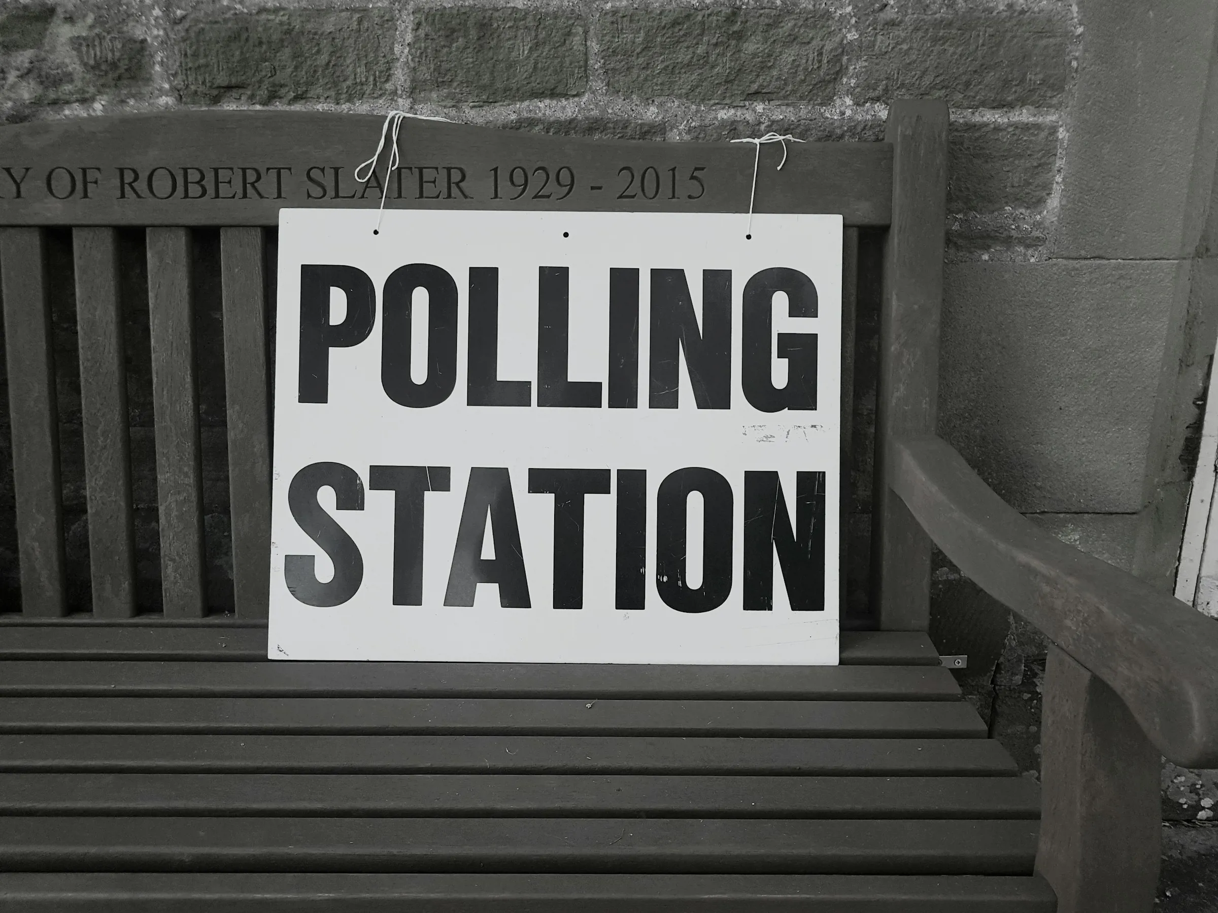 A sign on a wooden bench saying "Polling Station".