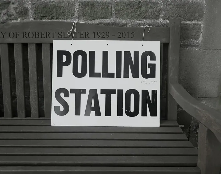 A sign on a wooden bench saying "Polling Station".